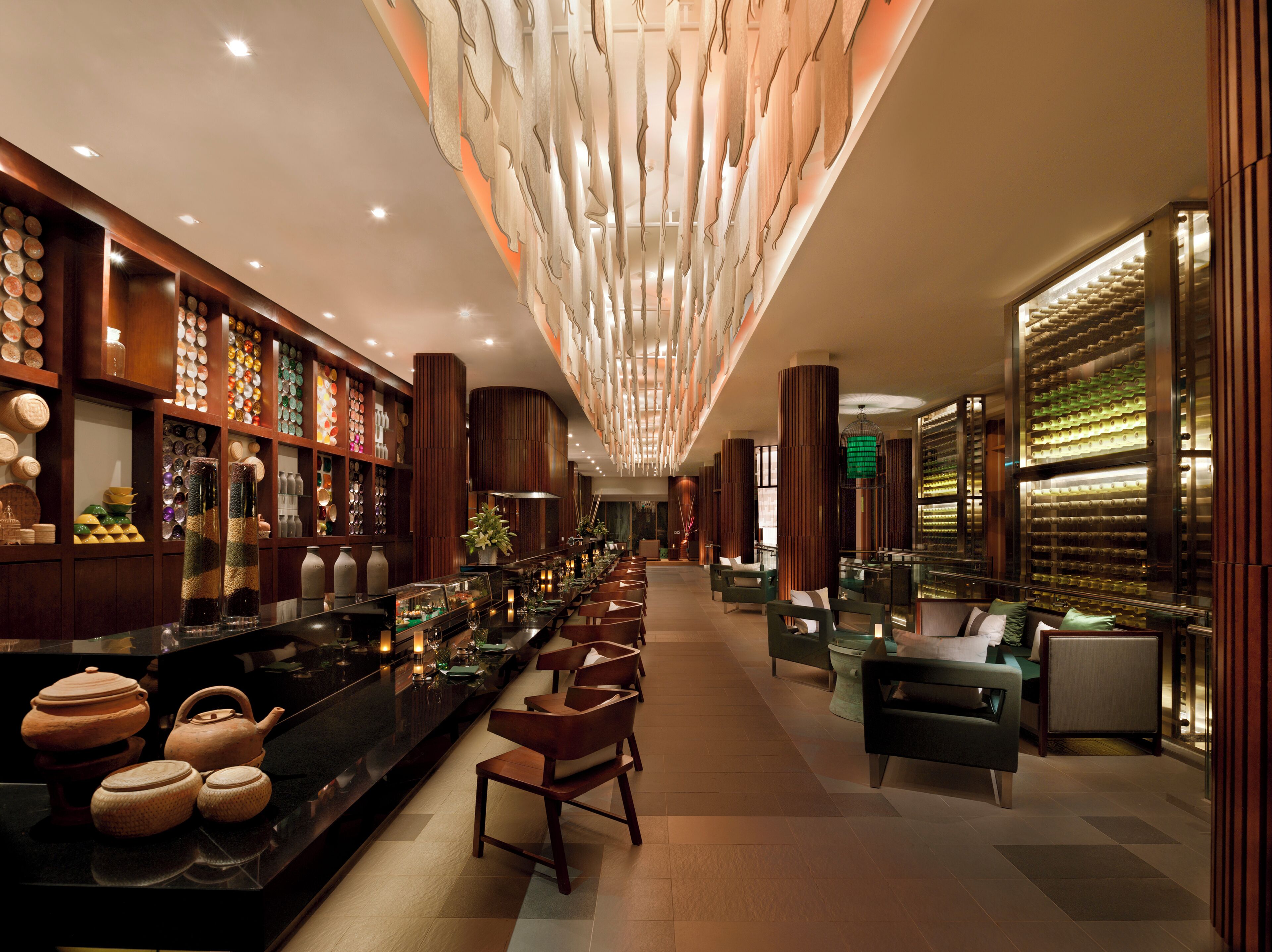 A modern hotel lobby with a long reception desk, seating area, and decorative wall panels.