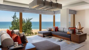 A modern living room with a large window overlooking the sea, a sofa set, a coffee table, and a lamp. - Angsana Lang Co (Hue)