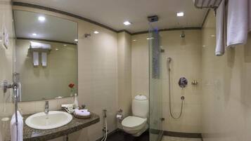 Une salle de bain moderne avec une douche à parois de verre, un lavabo doté d’un plan de travail en marbre et des toilettes.