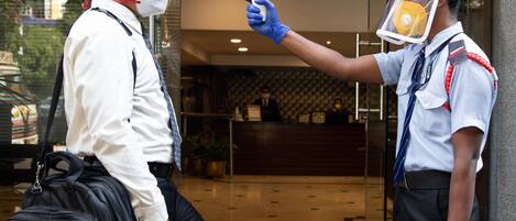 A security guard conducting a temperature check on a person entering a building.