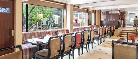 Een restaurant met zitplaatsen in hokjes en aan tafels, een bordje voor een opslagruimte en grote ramen met uitzicht op buiten.