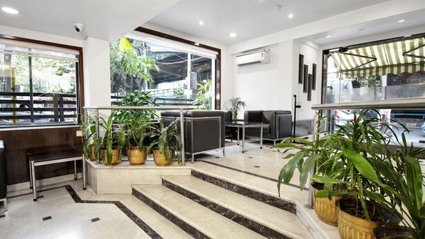 A hotel lobby with marble steps, potted plants, a reception desk, and large windows offering a view of the outdoors. - Hotel Casa Fortuna (Kolkata)