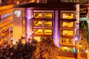 Un hotel moderno con varios pisos, grandes ventanales y un logo destacado en la fachada.
