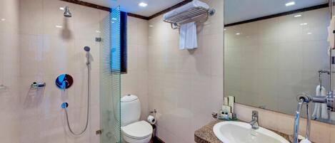 Un baño moderno con cabina de ducha de vidrio, inodoro, lavamanos con espejo y toallero.