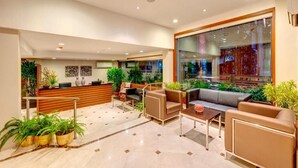 A modern lobby with a reception desk, seating area, and potted plants. - Hotel Casa Fortuna (Kolkata)