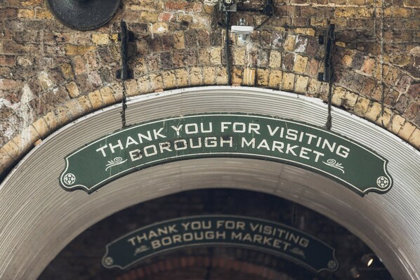 A circular metal sign with the text "THANK YOU FOR VISITING BOROUGH MARKET" mounted on a brick wall.