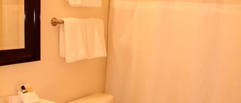 Un baño con inodoro, lavamanos y cortina de ducha.