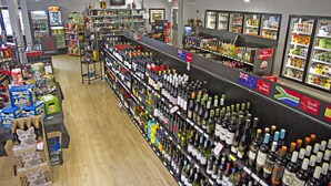 En købmand med hylder fyldt med forskellige flasker og kasser med alkohol.