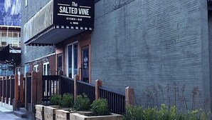 A building with a sign reading "The Salted Vine Kitchen Bar" and a wooden fence with planters.
