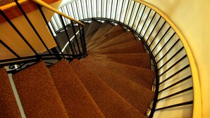 En spiraltrappe med gelænder og tæppede trin.