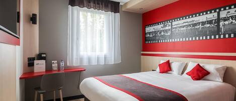 A hotel room with a bed, a desk, and a window with curtains.