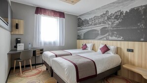 A hotel room with two beds, a desk, a chair, a telephone, and a window with a view of a bridge. - Brit Hotel Le Cottage (Arnage)