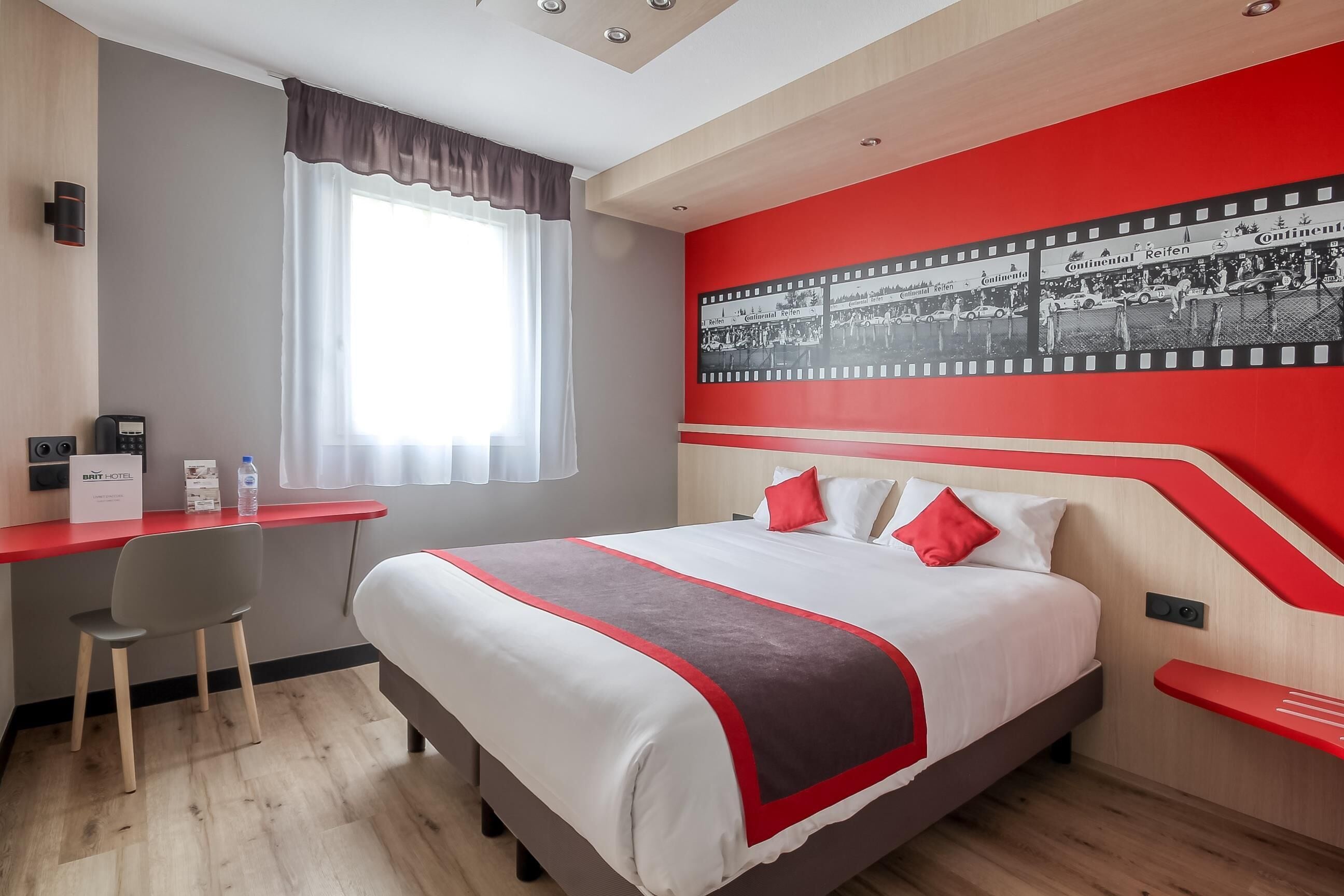 A hotel room with a bed, a desk, and a chair.