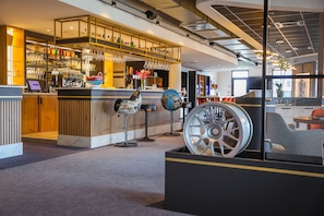 A modern bar area with a counter, bar stools, and a large decorative wheel.