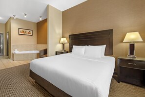 Ein Hotelzimmer mit einem großen Bett, einem Nachttisch mit Lampe, einem Bad mit Badewanne und einem Wandbild.