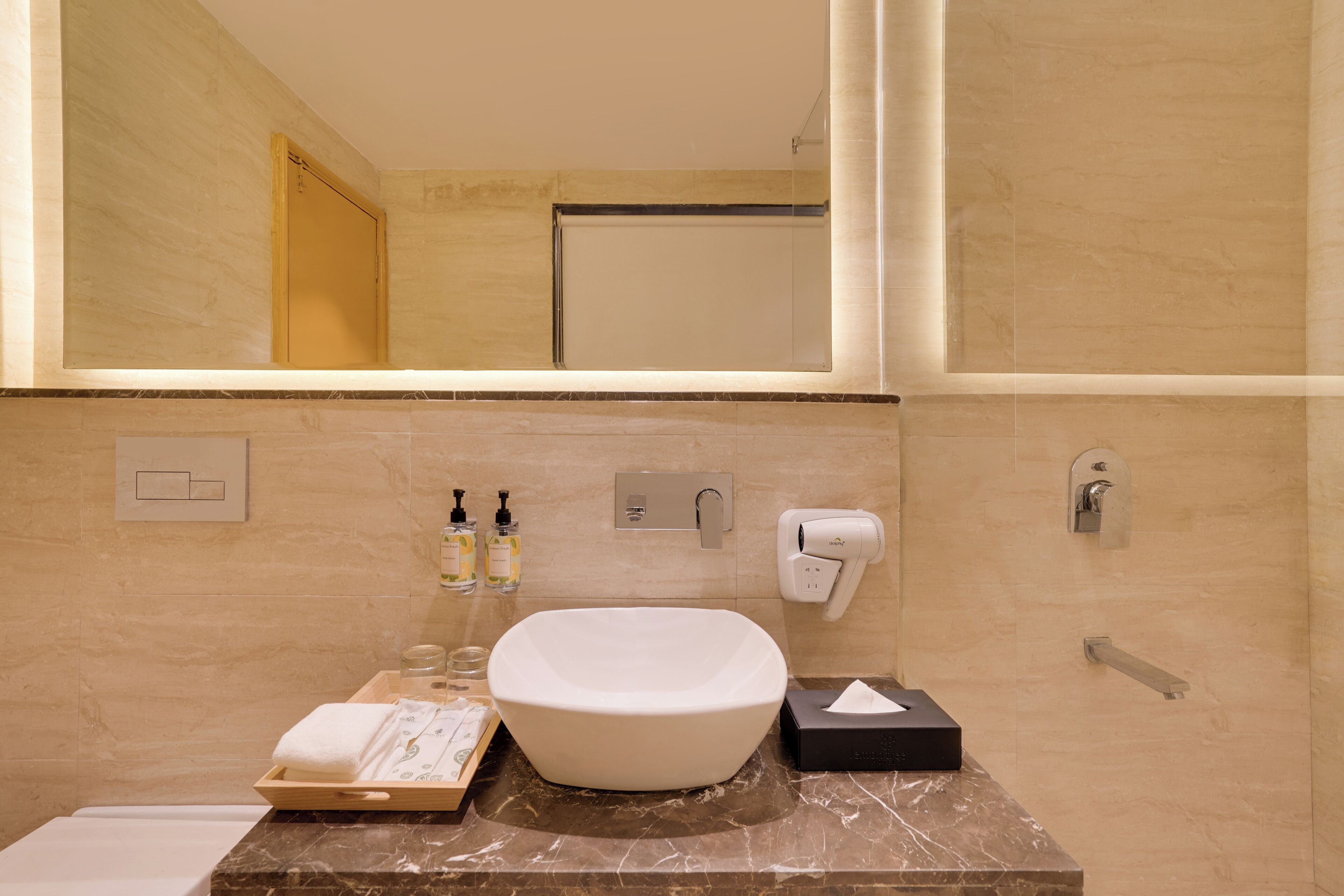 A modern bathroom with a large mirror, a white sink, and a towel rack.
