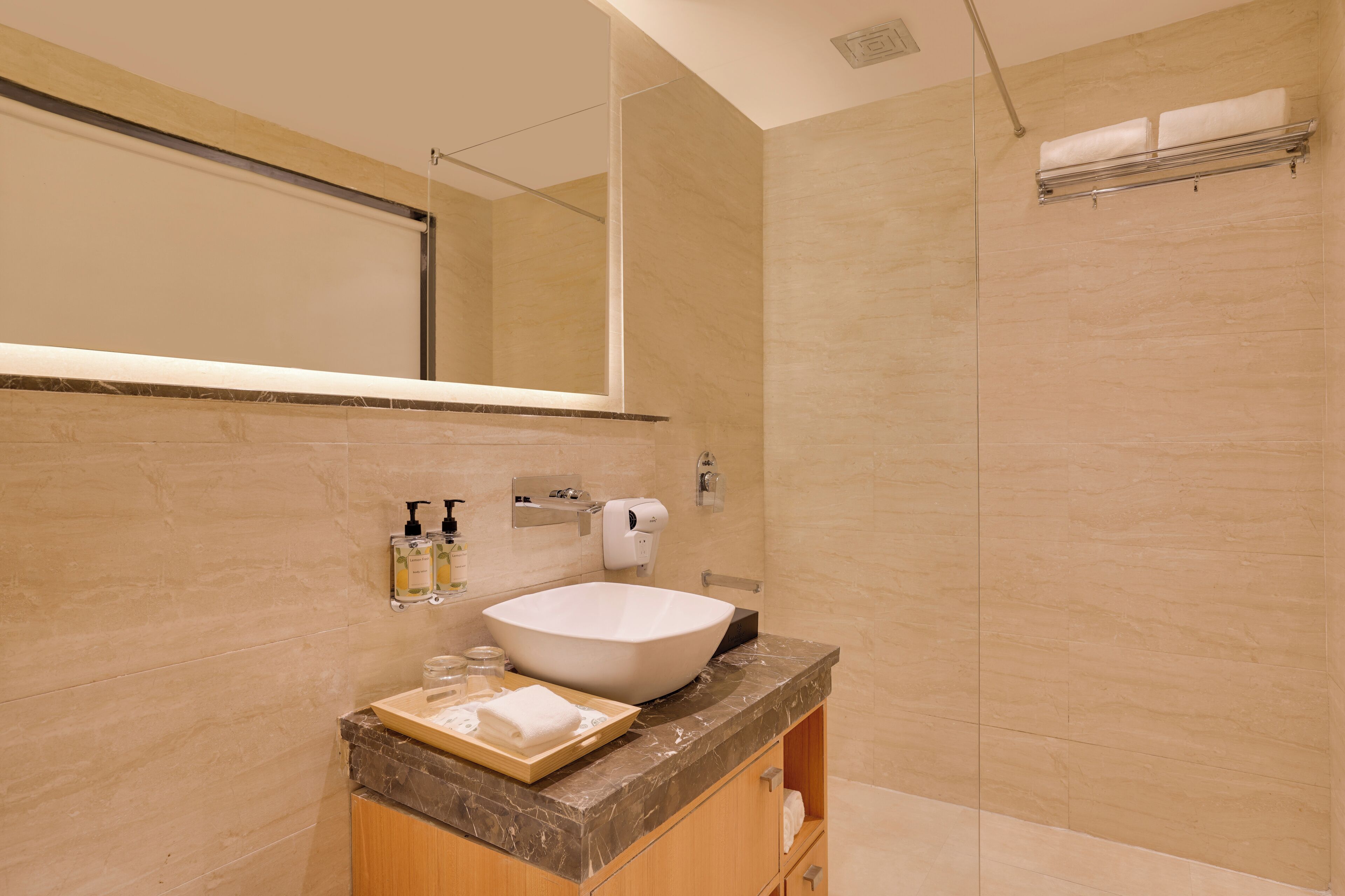 A modern bathroom with a large sink, mirror, and shower.