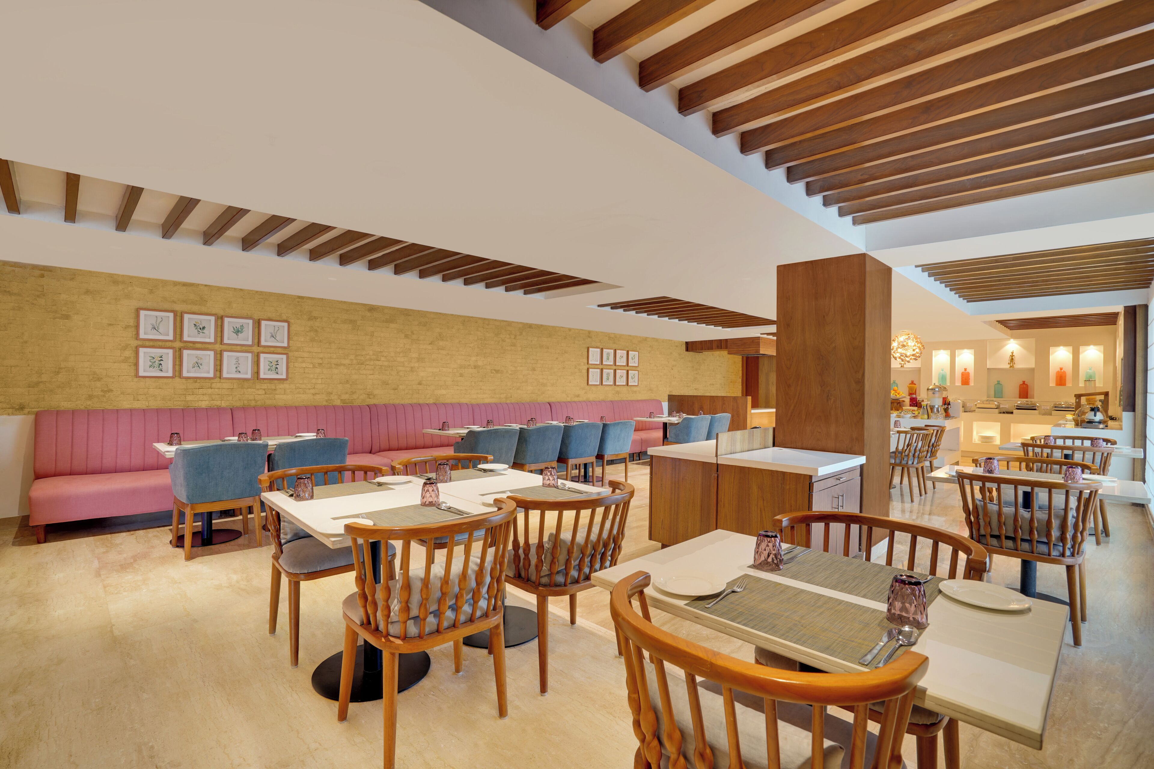 A restaurant with wooden tables and chairs, a pink booth seating area, and framed pictures on the wall.