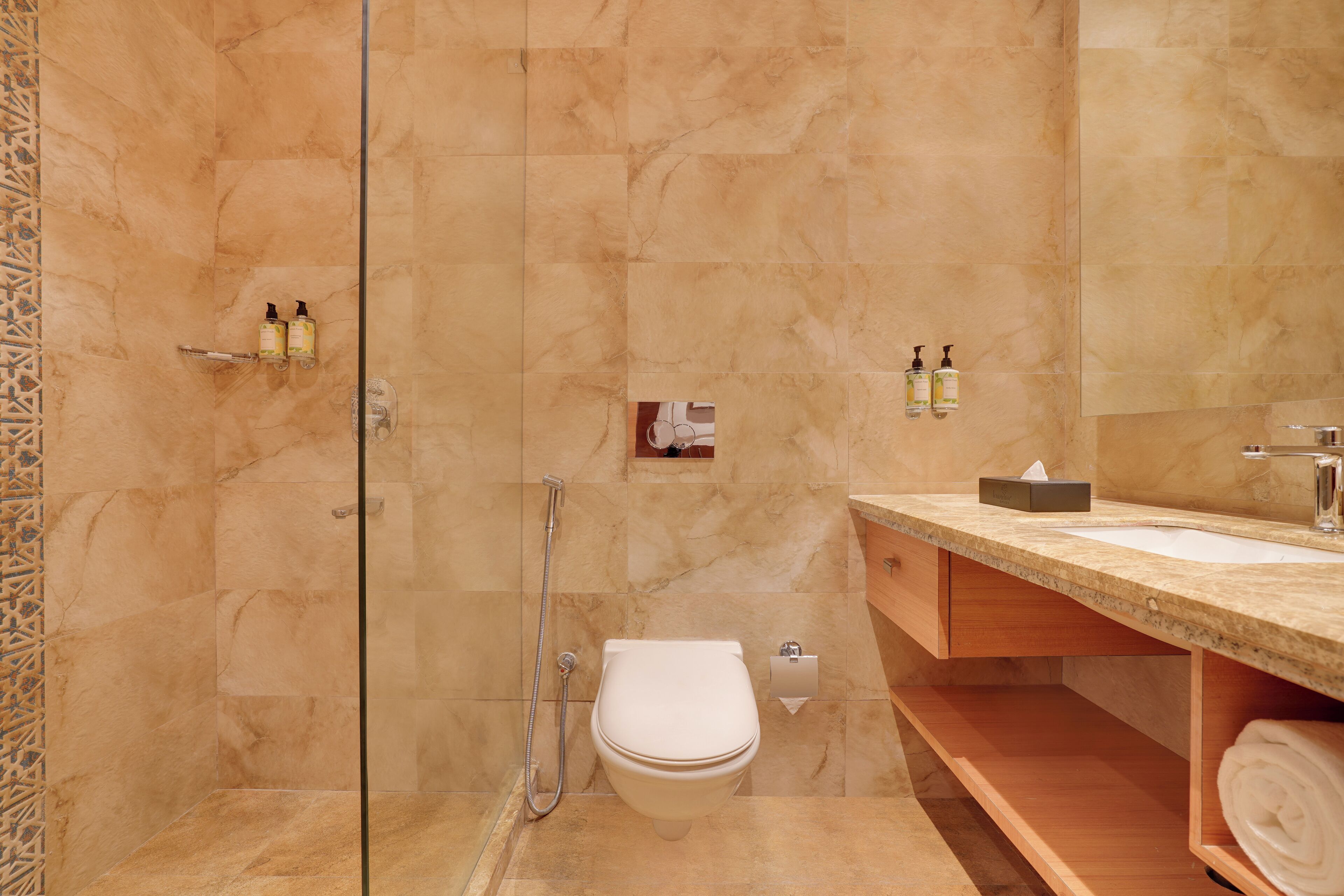 Un baño moderno con ducha envuelta en vidrio, inodoro y tocador con lavabo y espejo.