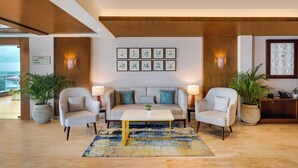 A modern lobby with a sofa, two armchairs, a coffee table, and potted plants. - Lemon Tree Resort, Mussoorie (Dehradun)