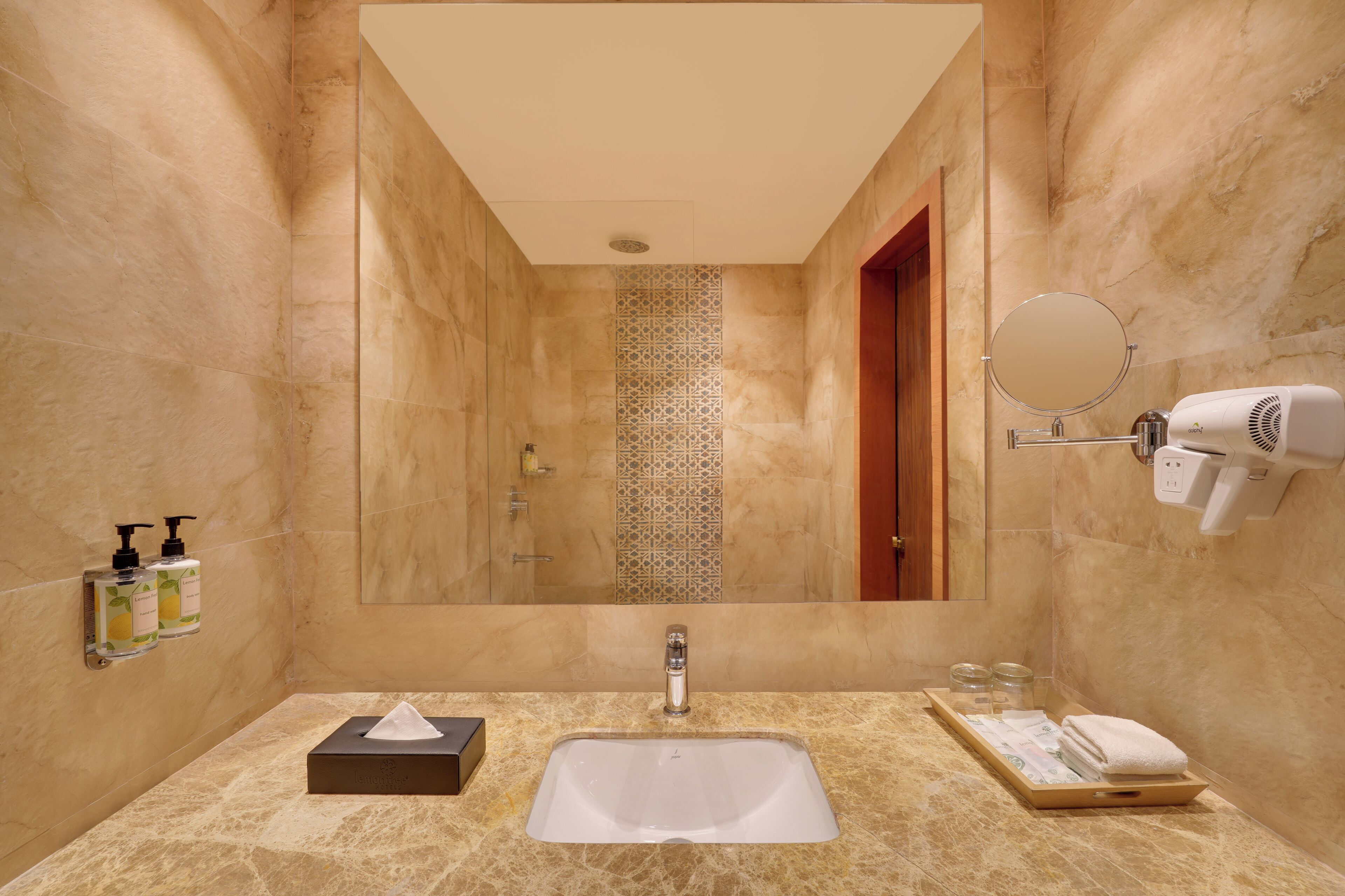 A bathroom with a marble sink, a mirror, a hairdryer, and toiletries on the wall.