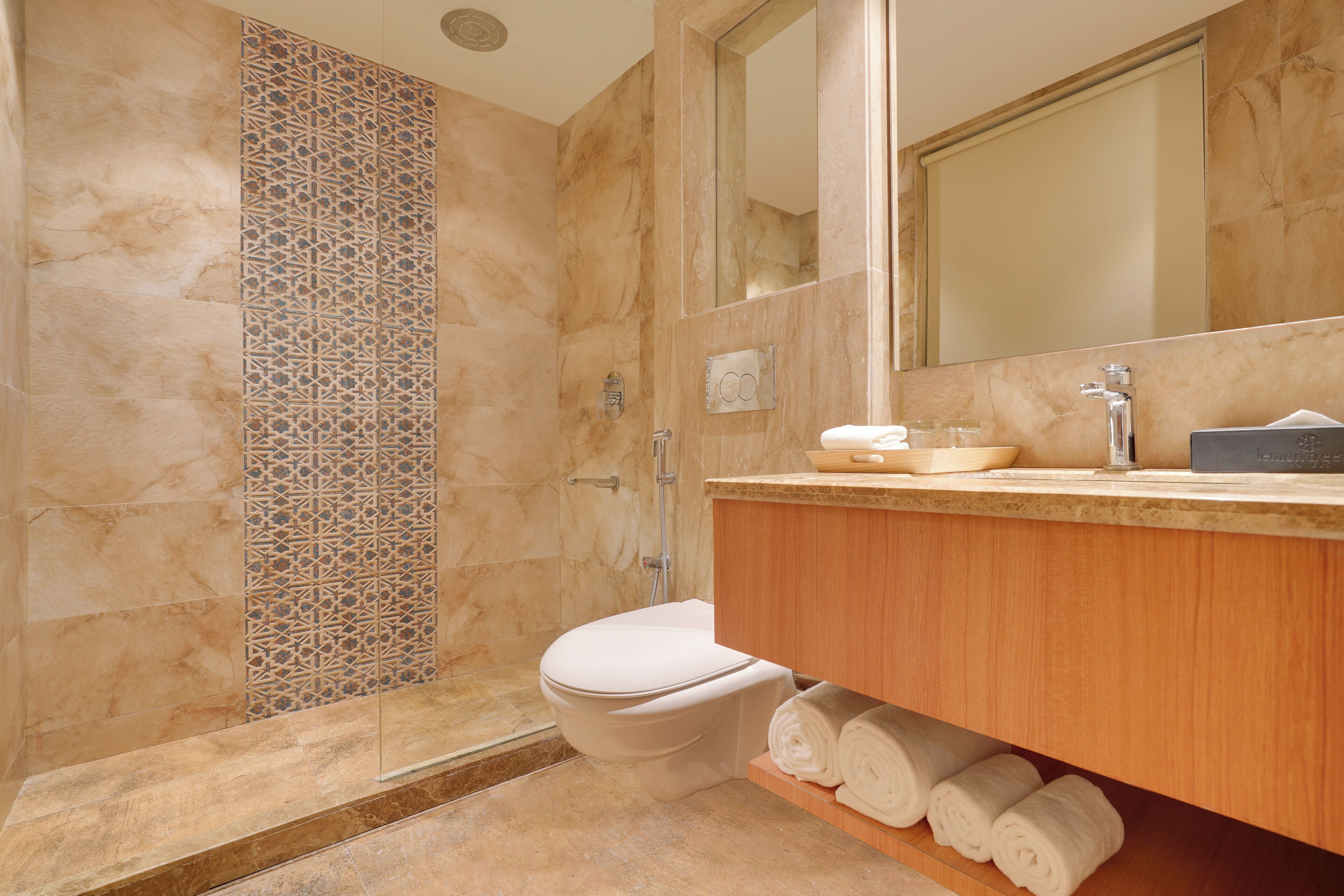 A bathroom with a toilet, a shower, and a vanity with a mirror.