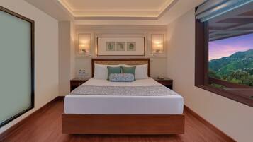 A modern hotel room with a large bed, bedside tables, a view of the mountains, and framed artwork on the wall.