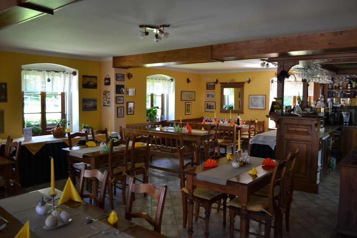 Un comedor con mesas y sillas de madera, paredes amarillas y cuadros en las paredes.