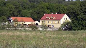 A rural house with a red roof, surrounded by a forested area.