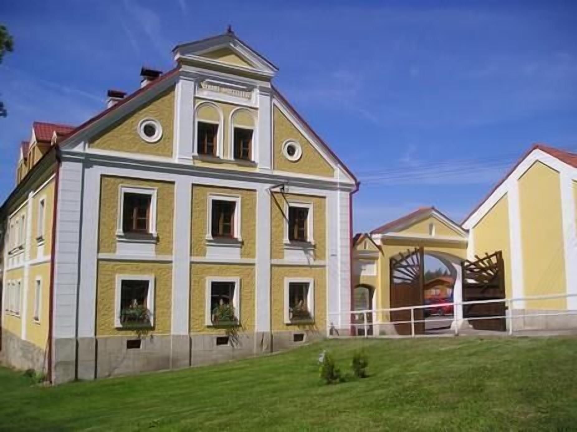 Um edifício com vários andares, fachada amarela e detalhes brancos, apresentando um design simétrico com entrada central e várias janelas.