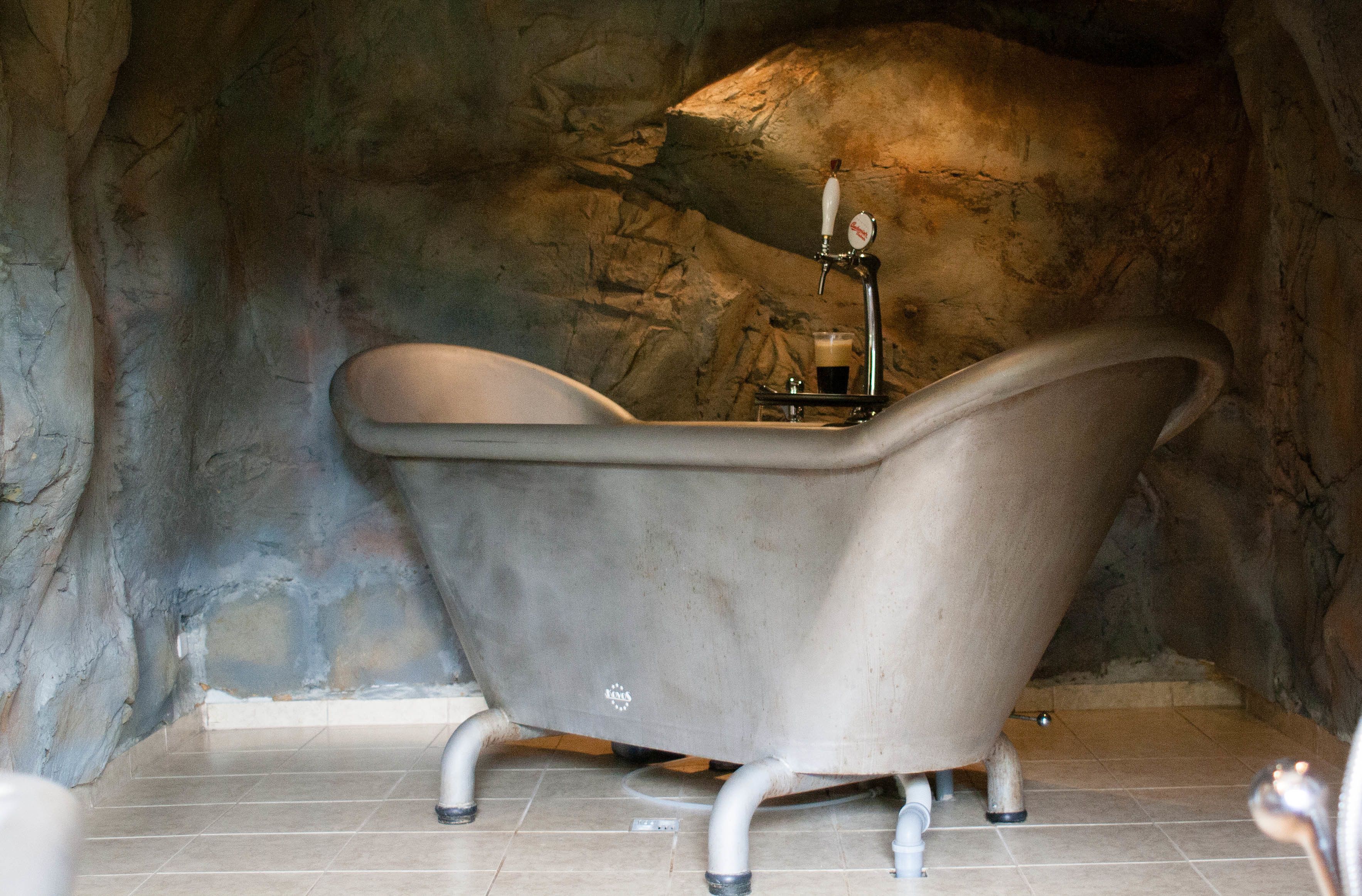 Une baignoire sur pieds, de style ancien, dans une salle de bain aux murs en pierre.