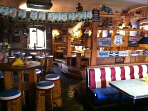 A restaurant interior with wooden booths, high stools, and a bar area.