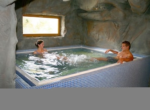 A hot tub with a tiled interior and a natural rock backdrop. - Hotel Stein (Cheb)