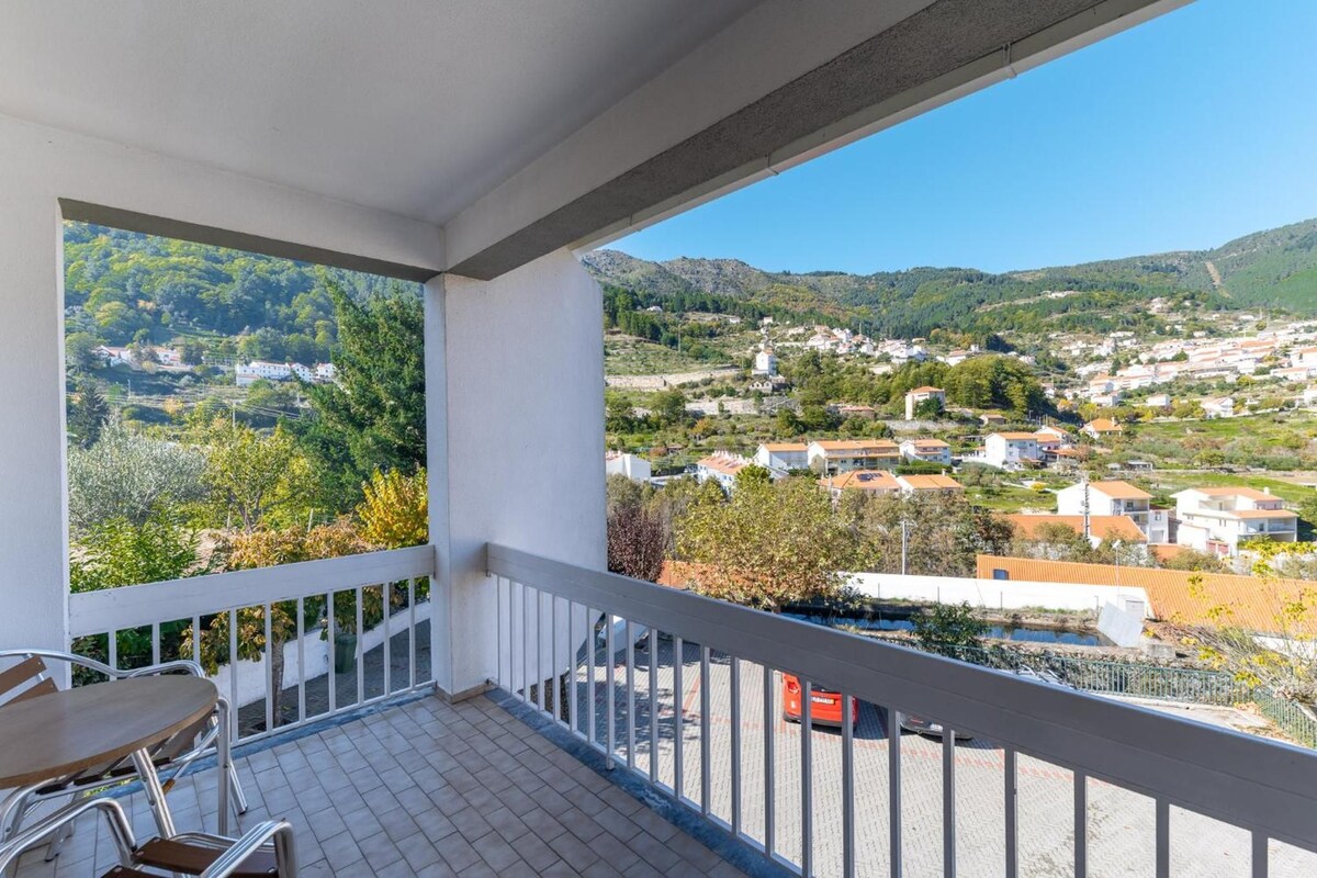 A balcony with a view of a town and hills.
