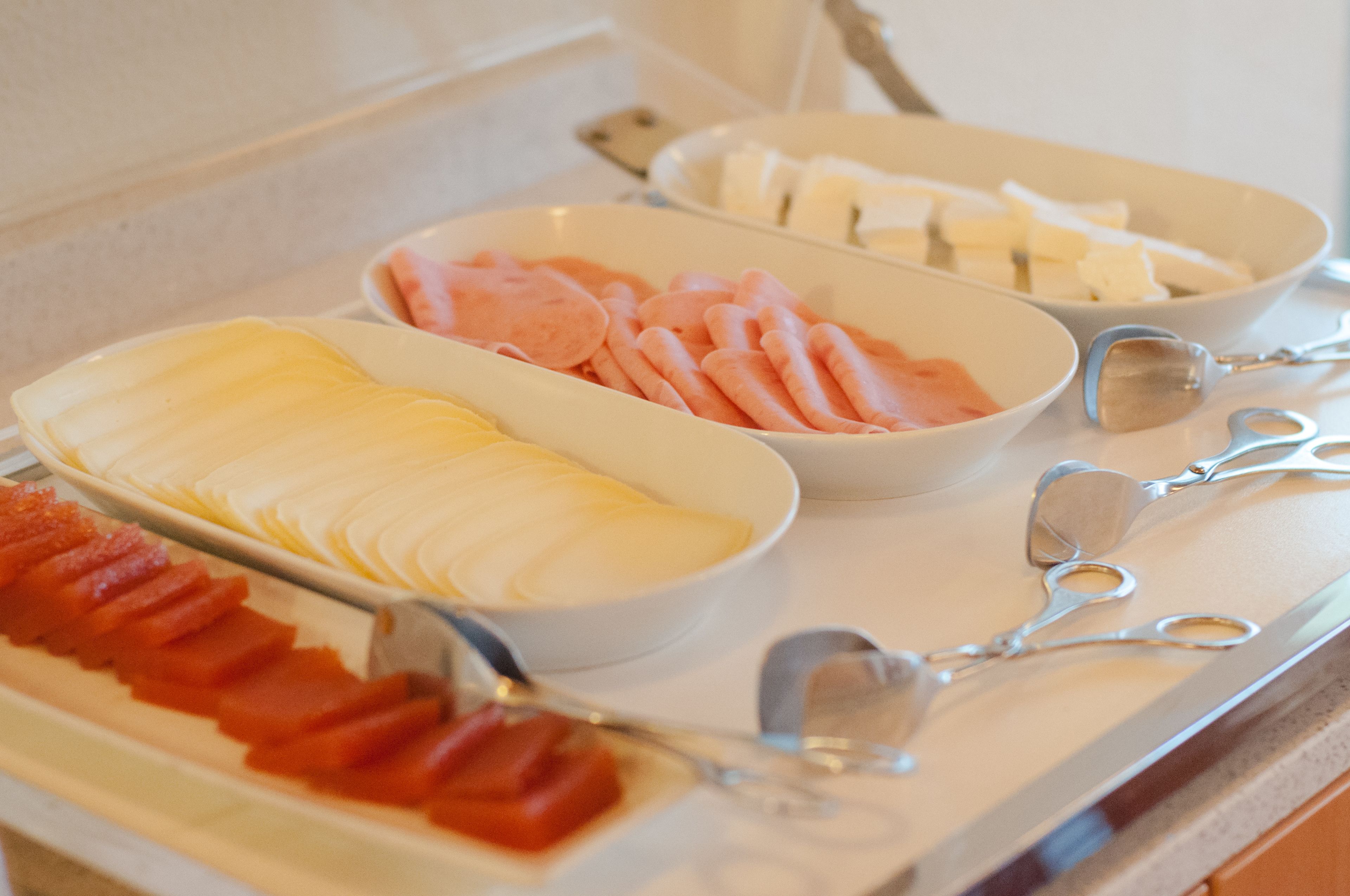 A buffet with various food items including sliced ham, cheese, and other deli meats.