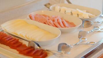 A buffet with various food items including sliced ham, cheese, and other deli meats.