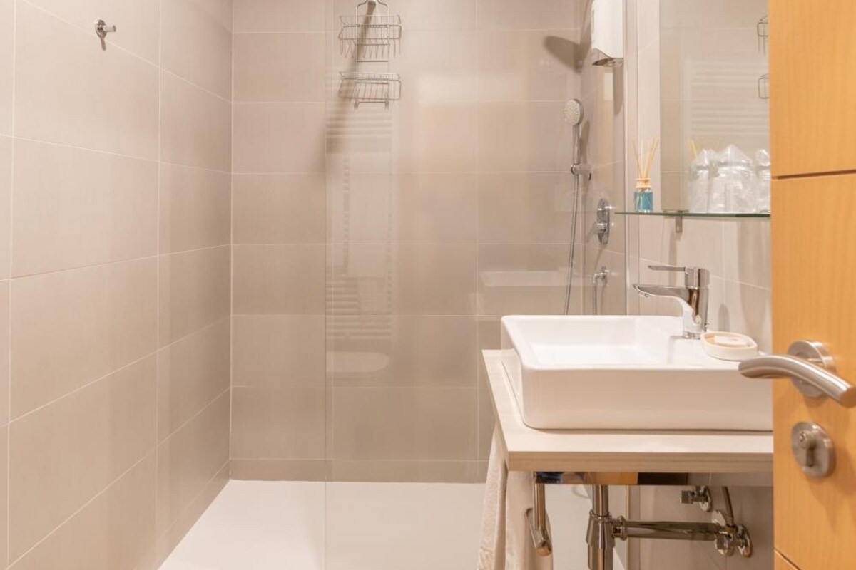 Un baño moderno con ducha, lavamanos y espejo.