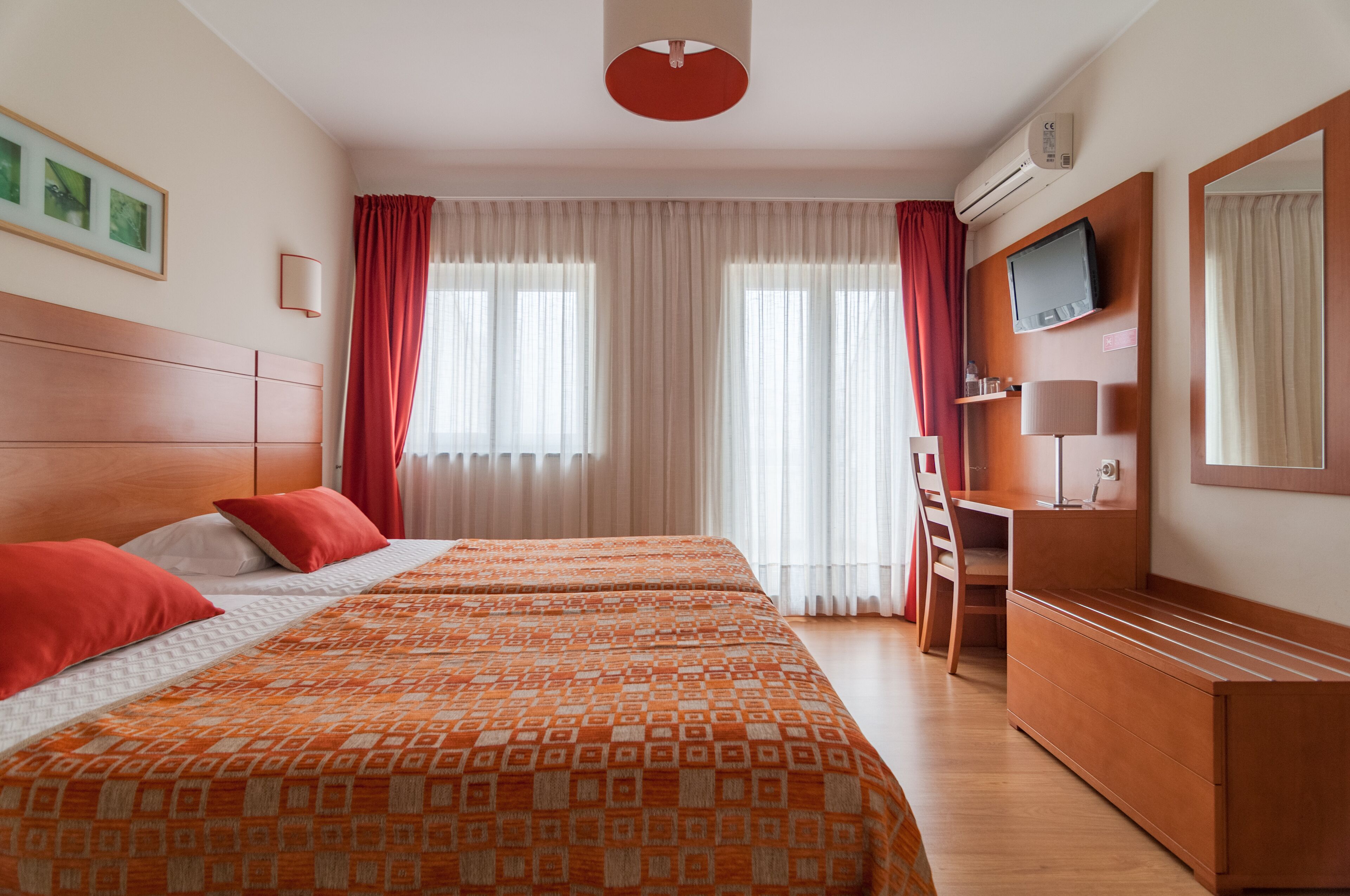 Habitación de hotel con dos camas, un escritorio, un televisor y un equipo de aire acondicionado.