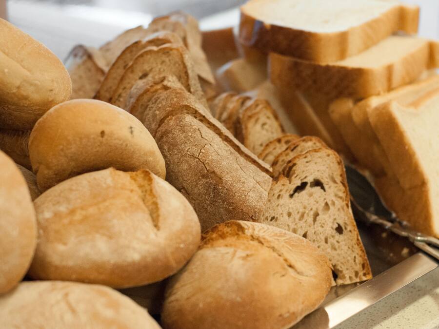 Diversos pães e fatias de pão em uma bandeja.
