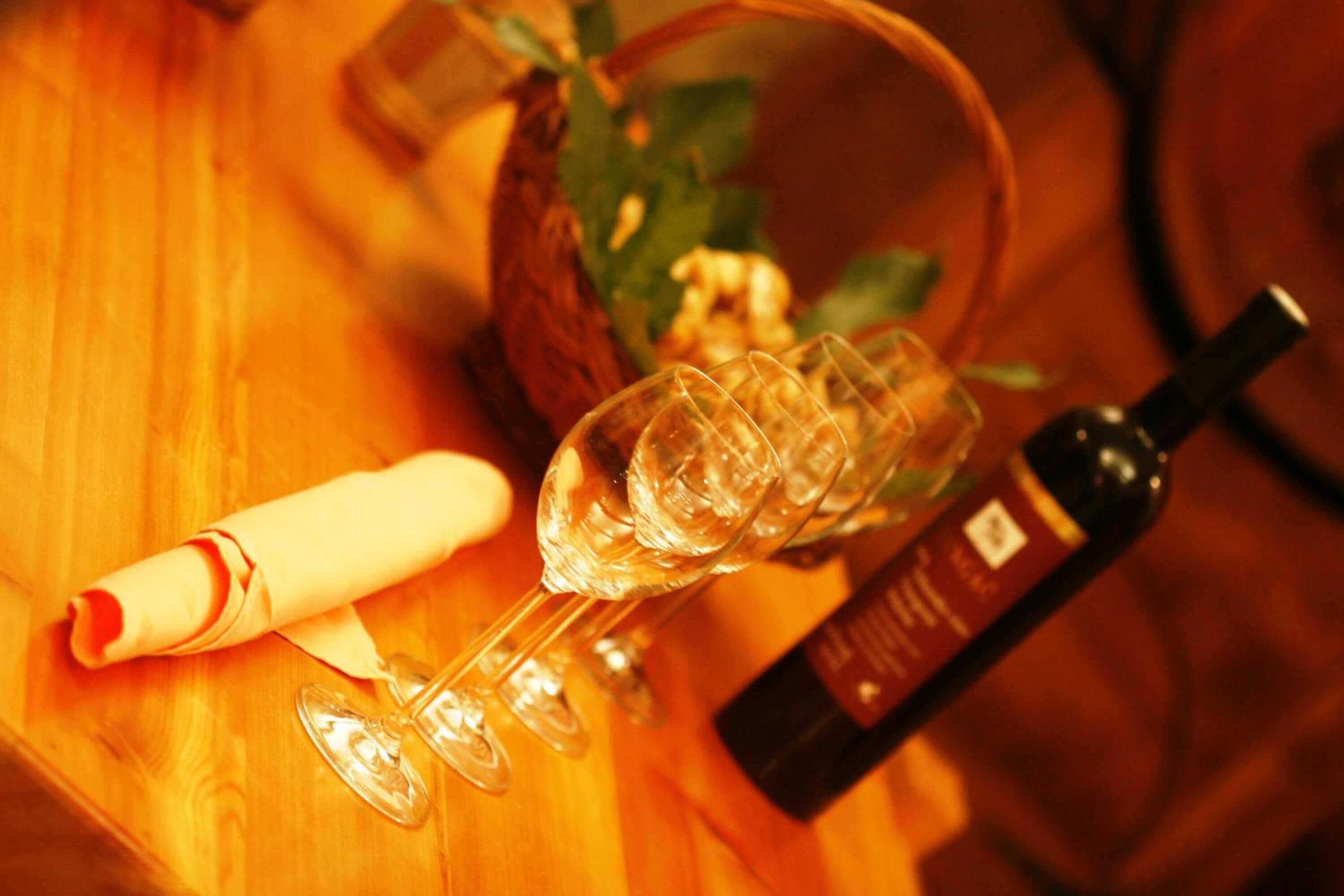 Un tavolo di legno con una bottiglia di vino, bicchieri e un tovagliolo arrotolato.