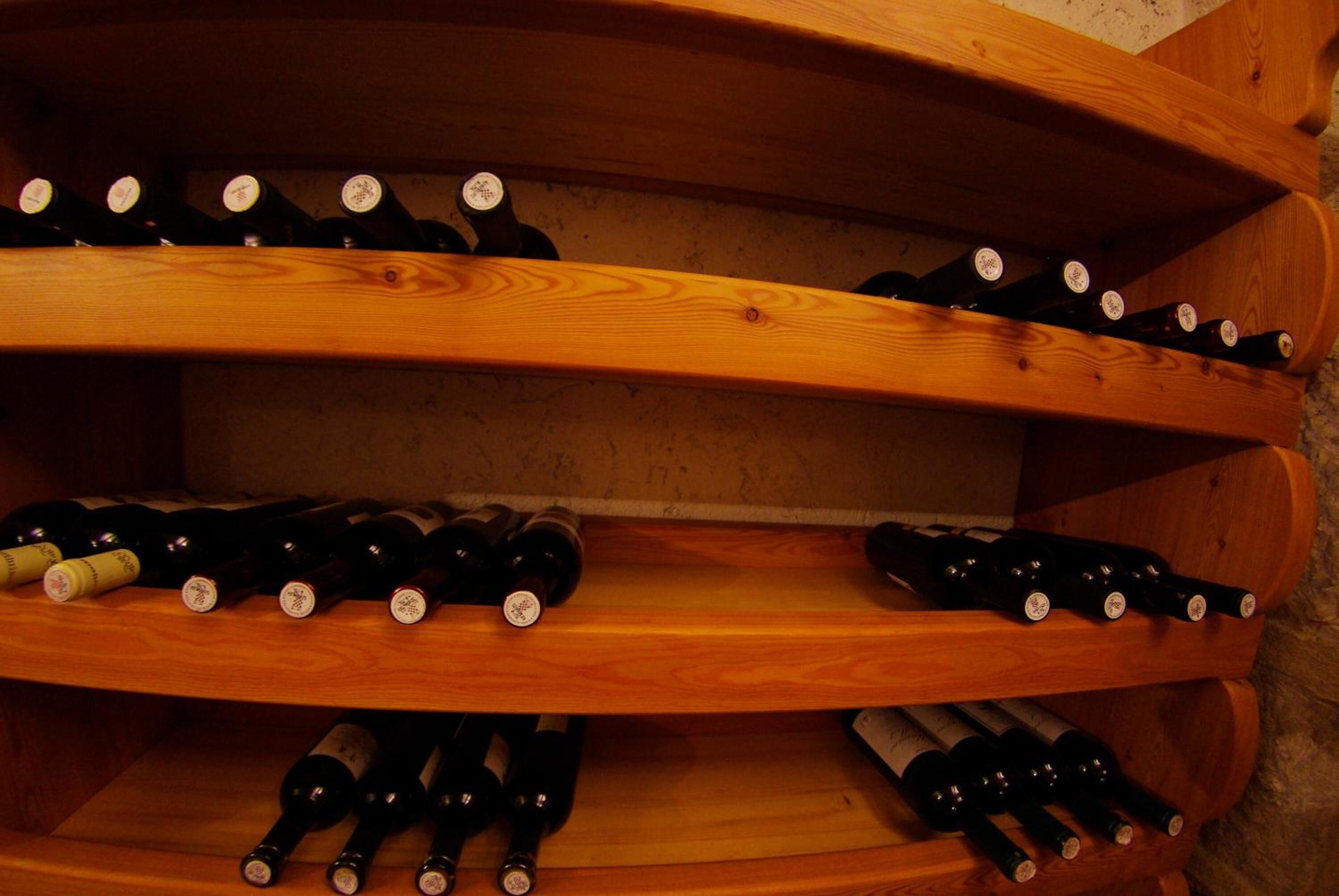 A wooden wine rack with multiple shelves holding bottles.