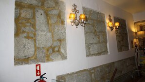 A hallway with stone walls and a fire extinguisher mounted on the wall. - Residencia Pedra Antiga (Porto)