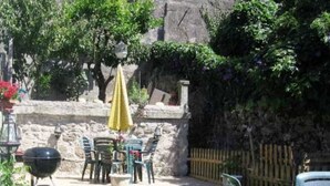 A patio area with a table and chairs, a barbecue grill, and a yellow umbrella. - Residencia Pedra Antiga (Porto)