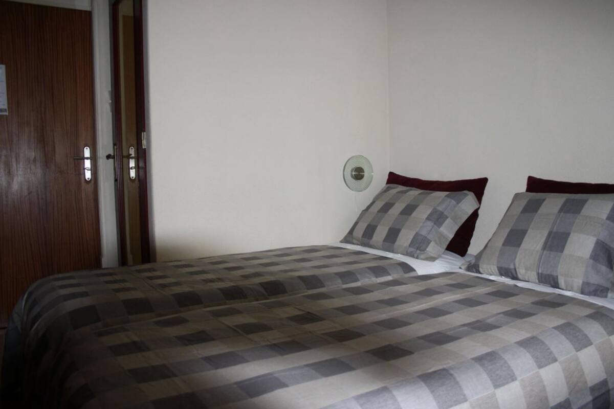 A bedroom with a bed, a wooden door, and a wall-mounted light fixture.