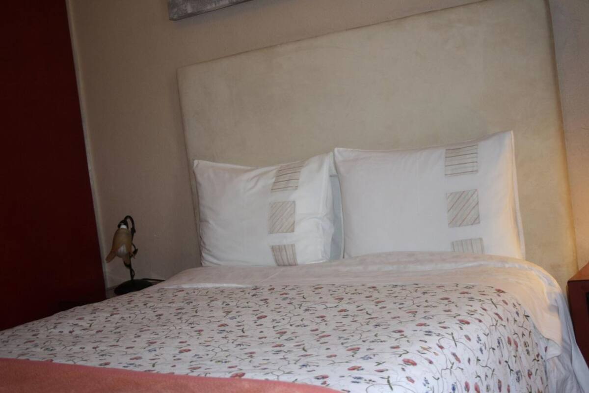 A bed with a floral-patterned bedspread and two pillows with striped patterns.