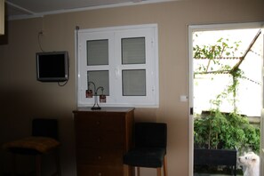 A room with a window, a television, a wooden cabinet, and a chair. - Residencia Pedra Antiga (Porto)