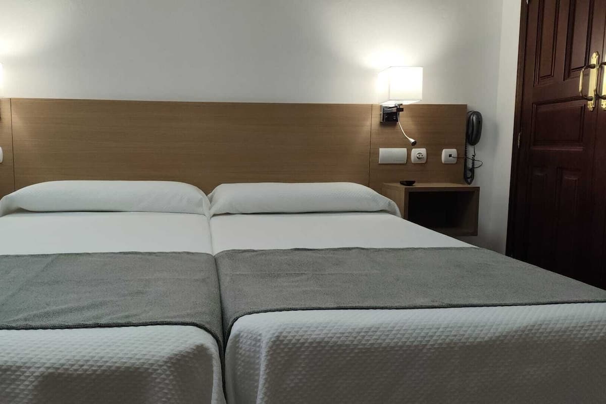 Habitación doble con dos camas, mesitas de noche y lámparas.