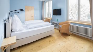 Una habitación con cama, escritorio, silla, televisión y ventana.