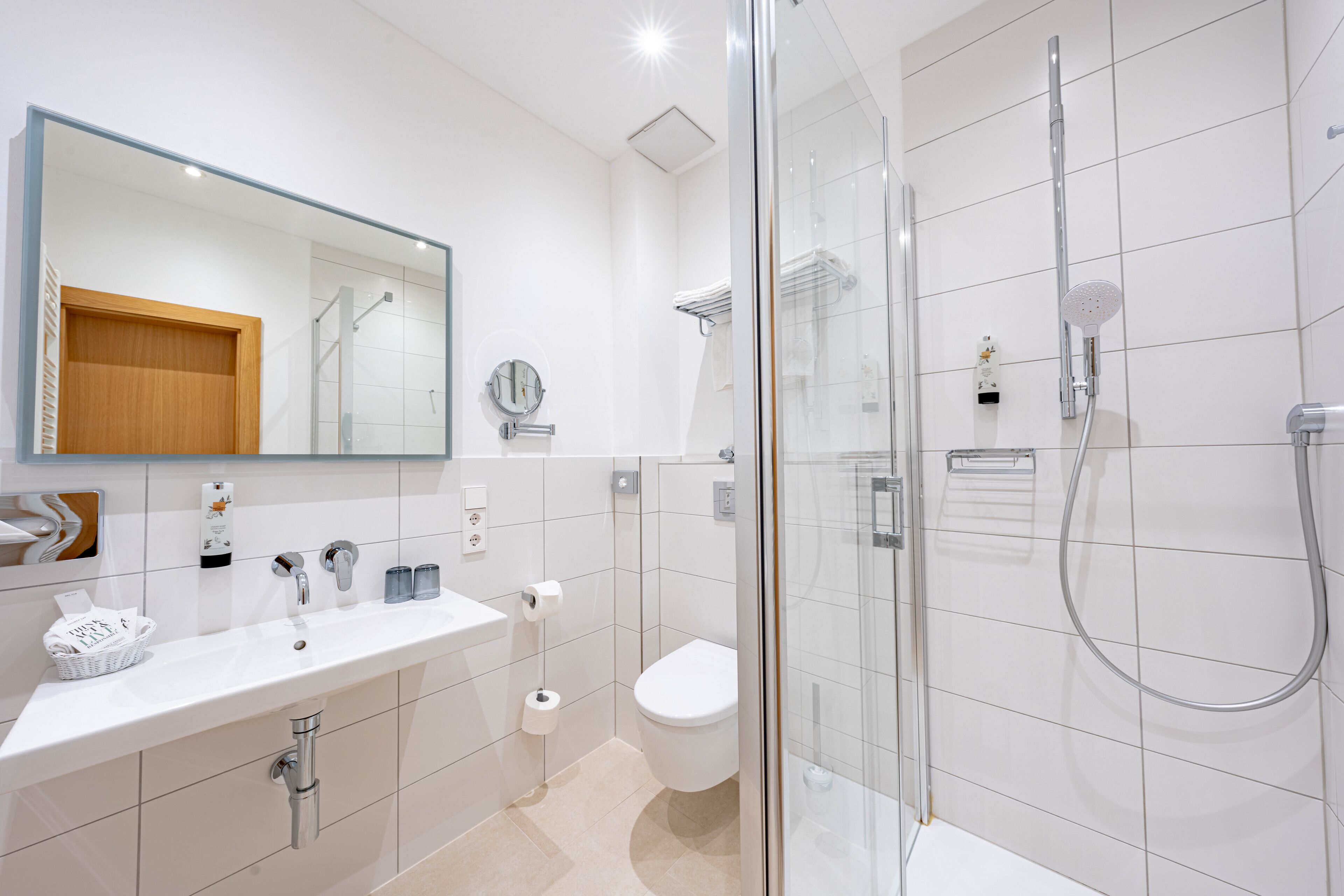 Une salle de bain moderne avec une douche à parois de verre, un lavabo blanc et des toilettes.