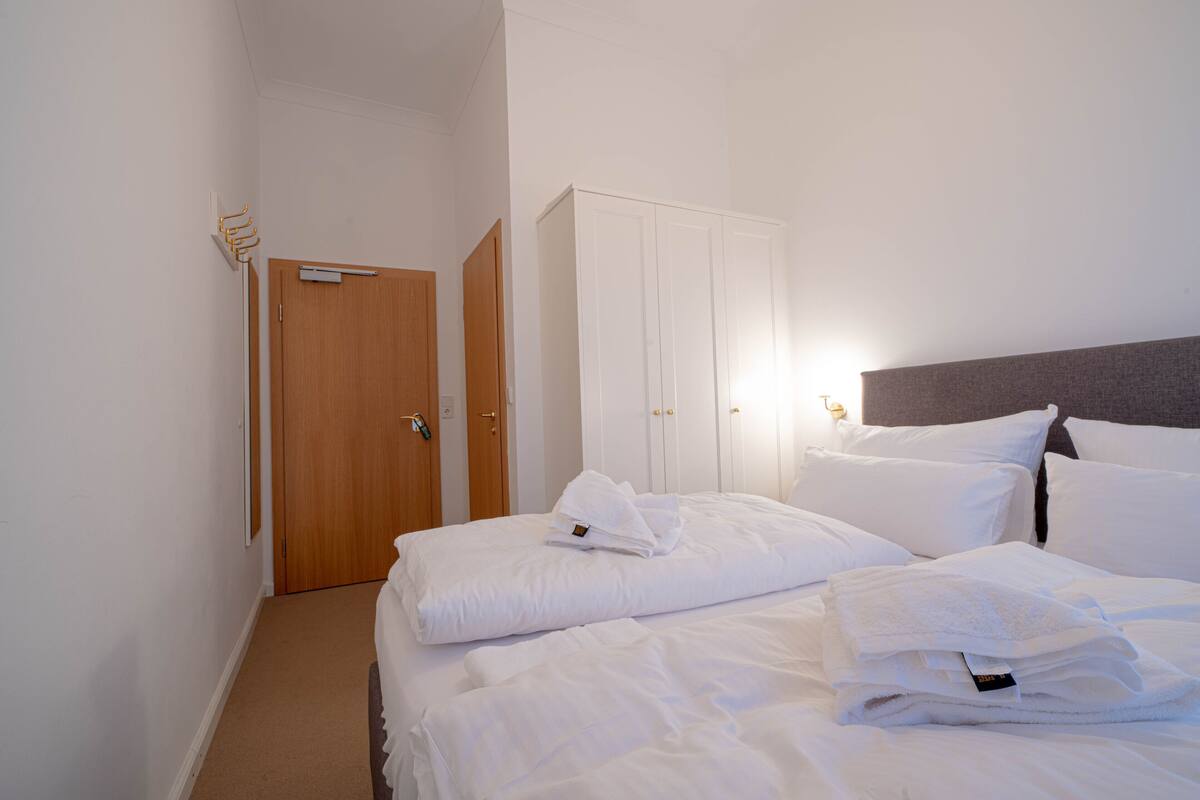 A hotel room with a bed, a wardrobe, and a coat rack.